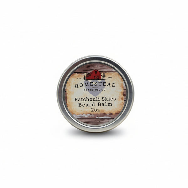 Homestead Beard Oil Co. Patchouli Skies Beard Balm container on a hay bale with a field and blue sky in the background