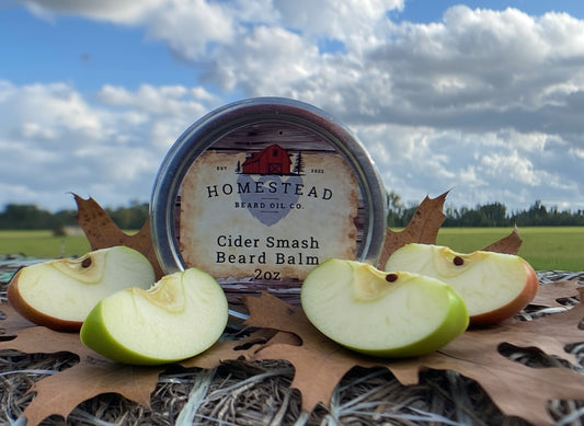 Homestead Beard Oil Co. Cider Smash Beard Balm container on a natural background with a cloudy sky.