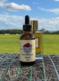 Bottle of Homestead Brand Oil Co. Gentleman's Mark oil with a field and blue sky in the background