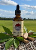 Bottle of Homestead Brand Patchouli Skies oil on a hay bale with a scenic background
