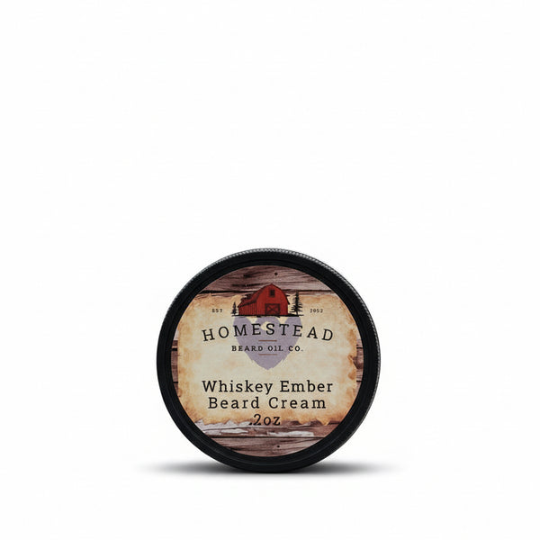 Homestead Beard Oil Co. Whiskey Ember Beard Cream container on a grassy field with a barn in the background.