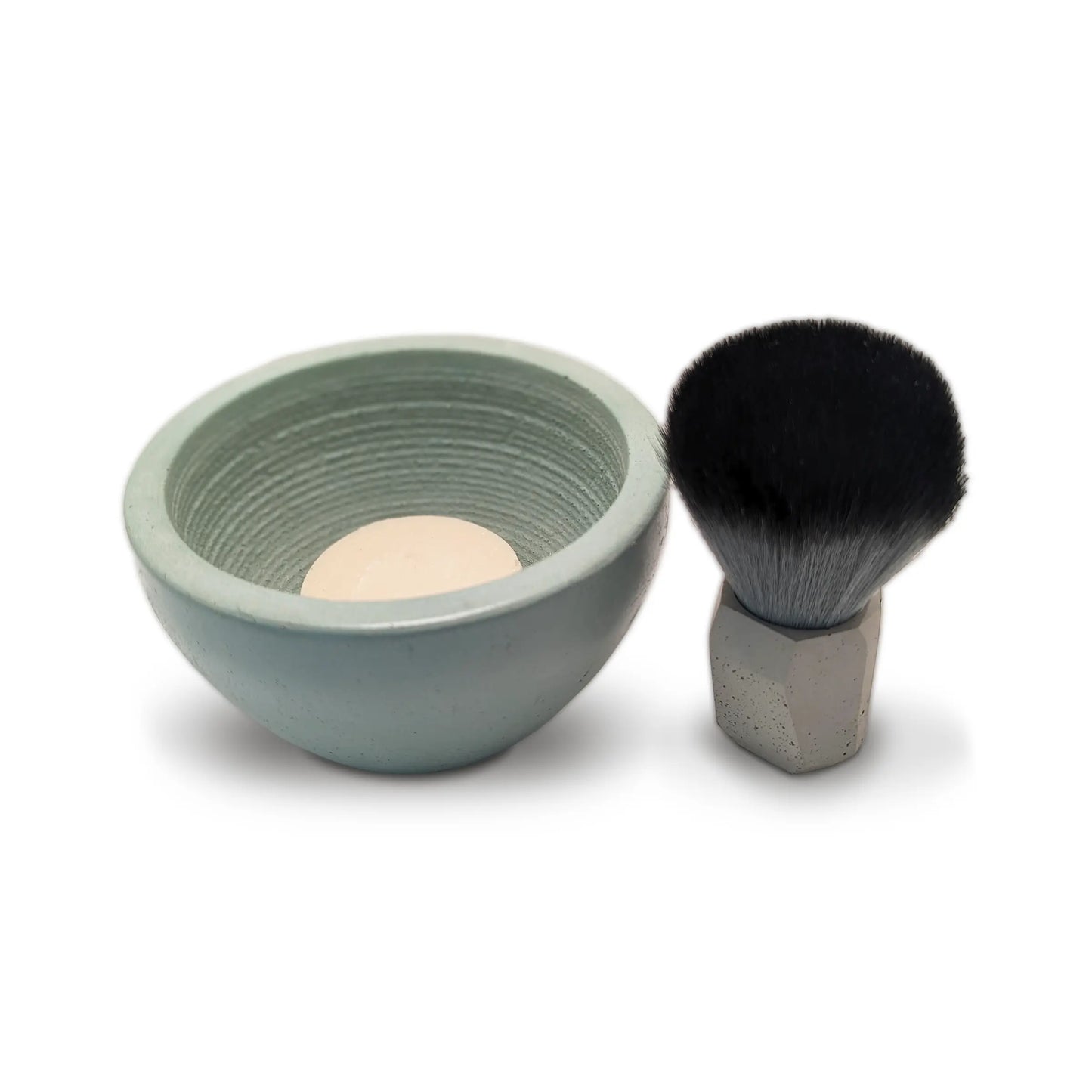 a small concrete shaving bowl with soap and brush