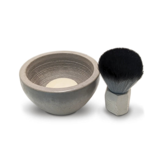 a small concrete shaving bowl with soap and brush